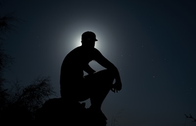 A silhouette of a figure standing under a full moon surrounded by mist.