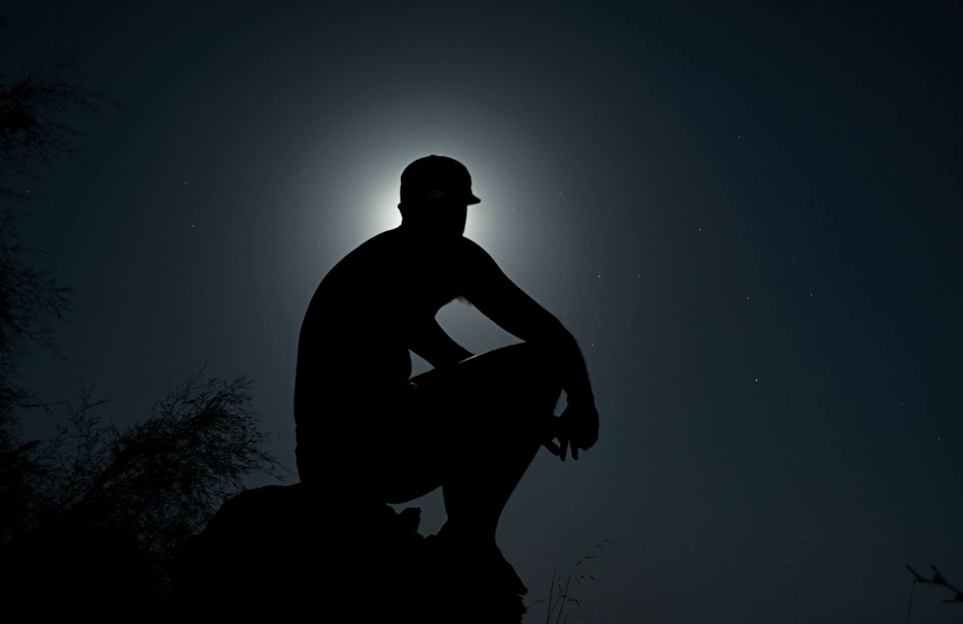 A haunting silhouette of a figure standing in front of an old, abandoned house under a full moon.