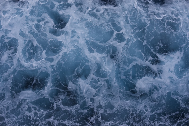 Blue ocean surface churned into lacey foam from above