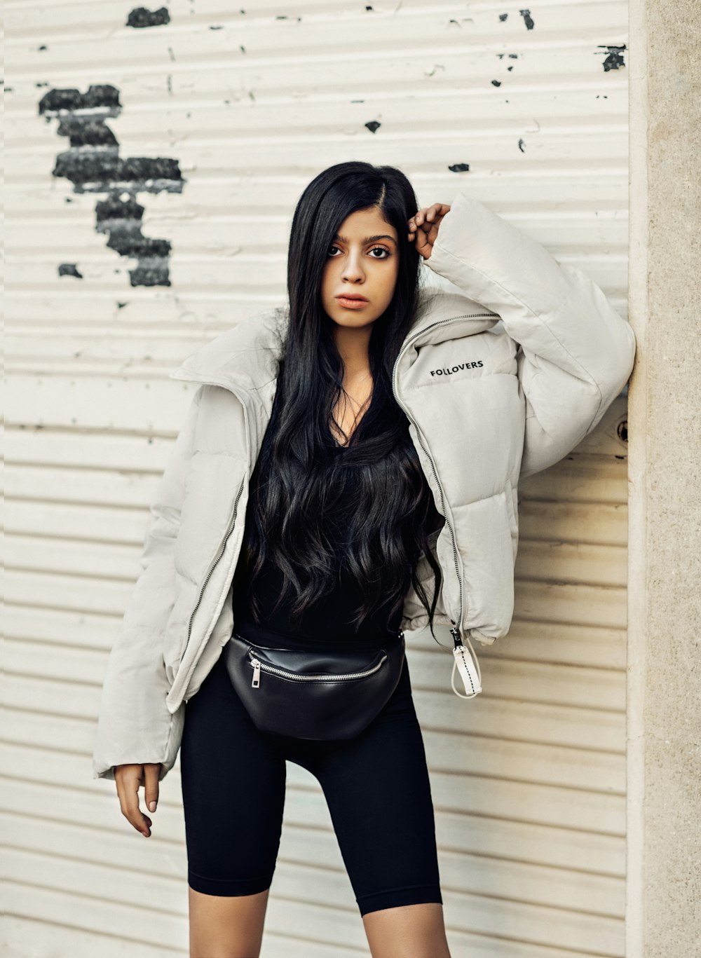 woman wearing gray puffer jacket, black shorts, and leather fanny pack