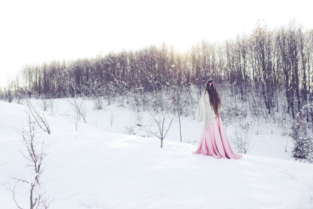 woman walking beside withered trees covered with snow