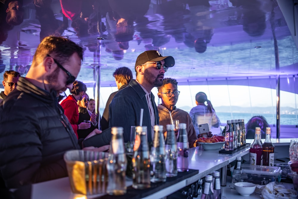 men sitting on bar with bottles on countertop