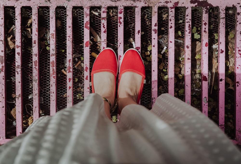 woman standing on pink grill wearing red flats