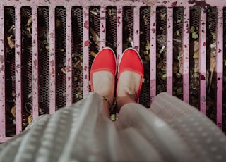 woman standing on pink grill wearing red flats