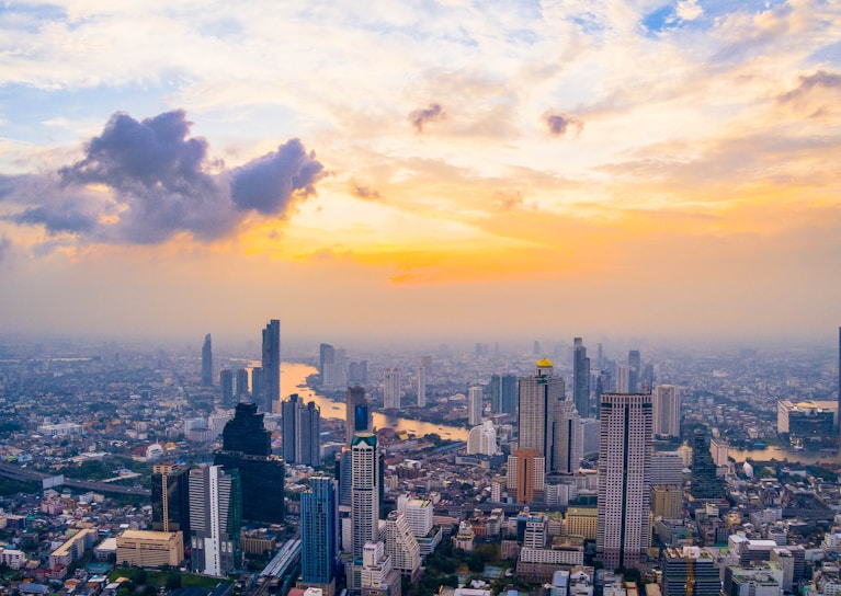 A vibrant city skyline at sunset with skyscrapers and a river.