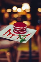Elegant flat lay of a red velvet dessert with subtle shadows on a black background.