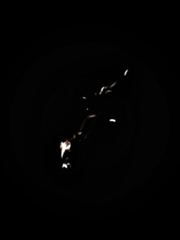 A dark background with a small flame or light source, creating a contrast against the black surroundings.