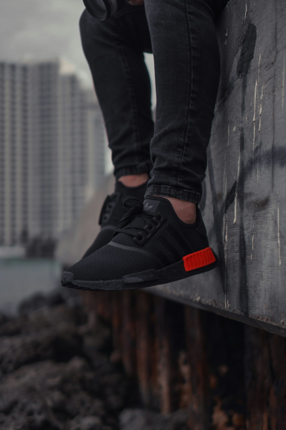 Foto Persona sentada en una superficie gris con zapatos adidas negros –  Imagen Gris gratis en Unsplash