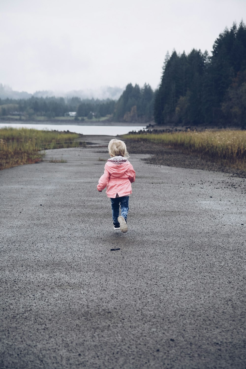 child running at road between grasses