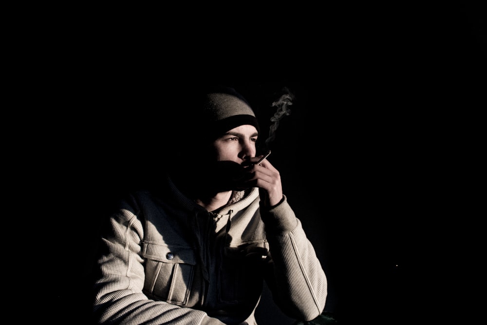 man in hoodie smoking cigarette stick