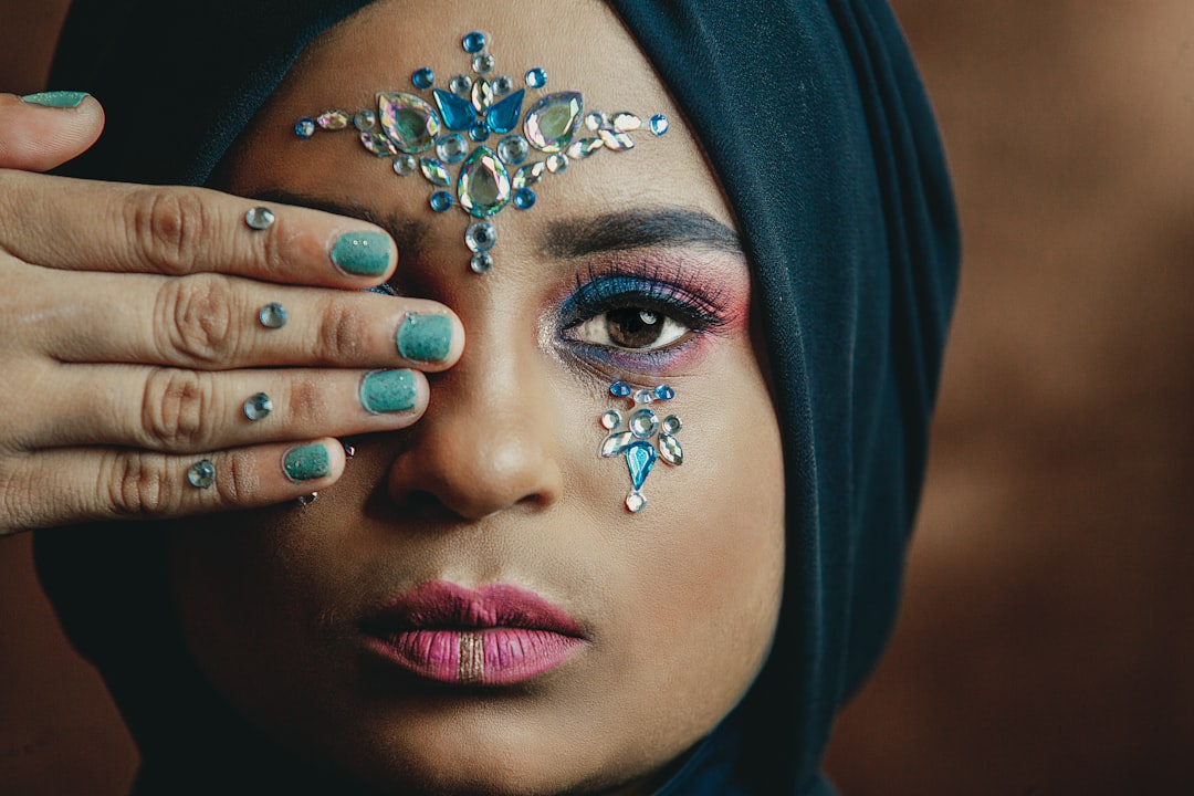 woman cover her right eye with her right hand and wearing blue hijab headdress