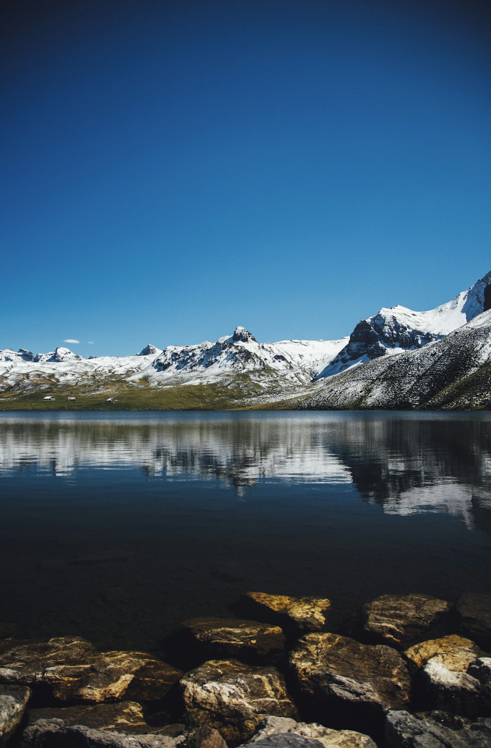 snow capped mountain range across clear lake