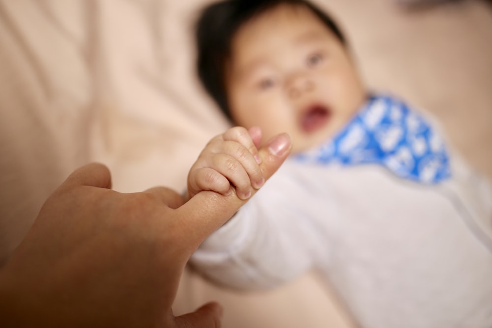 selective focus photography of baby holding index finger