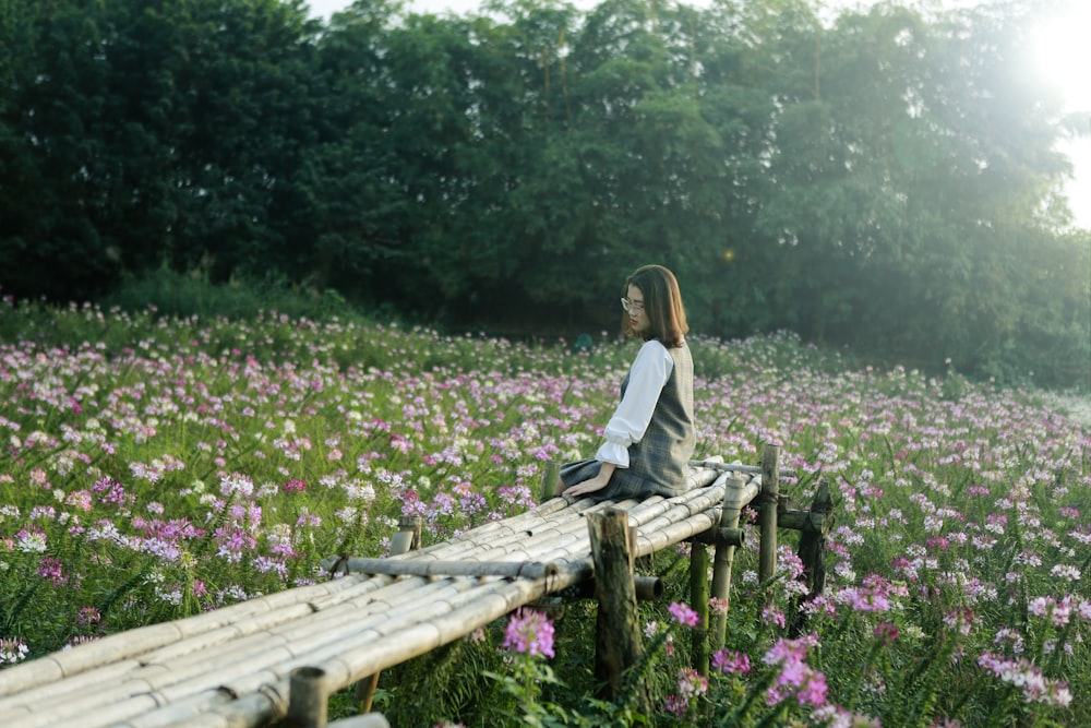 woman sitting on bamboo bench surrounded by purple flower field