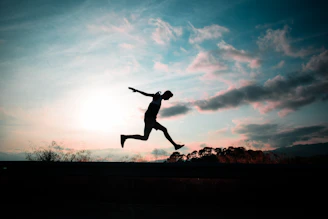 silhouette of man jumping during golden hour