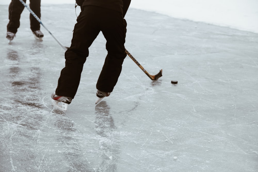 two persons playing hockey on ice field