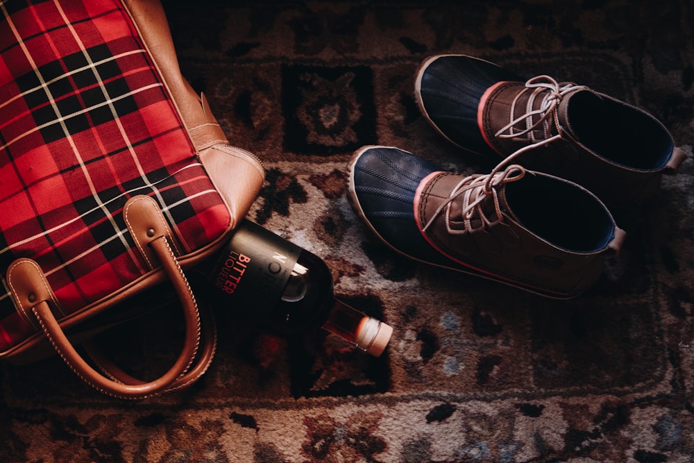 pair of brown-and-black suede boots beside red hand bag