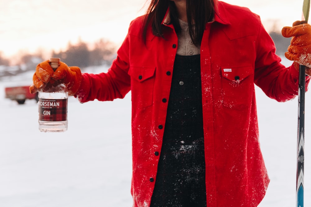 woman in red jacket holding gin bottle