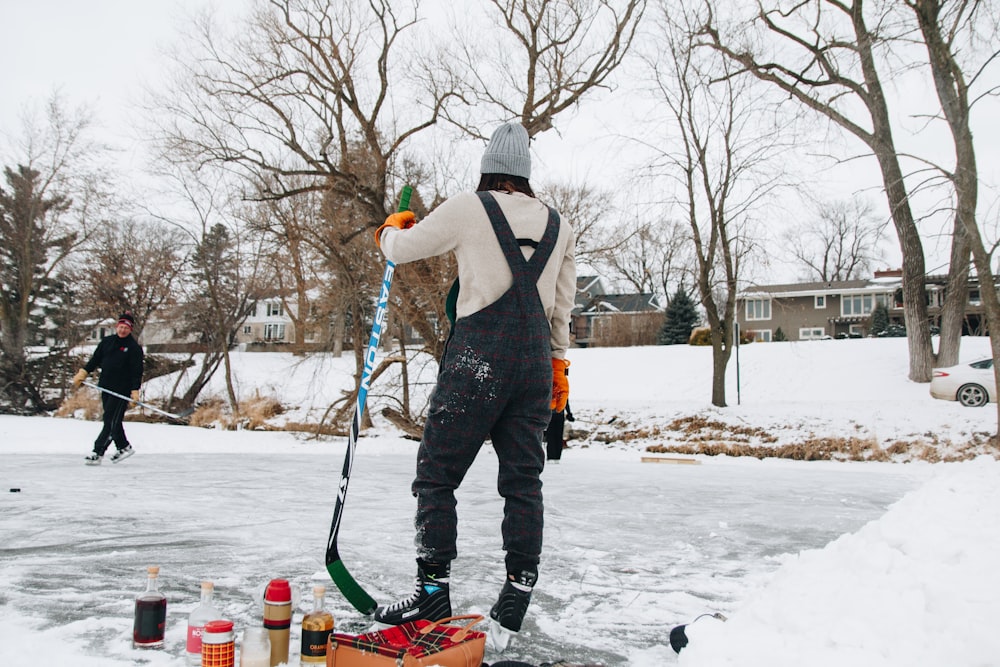 man standing in the middle of icy surface holding gray and green ice hockey stick