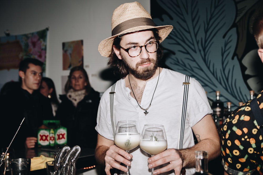 man holding two glasses with liquids