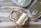 Three rectangular tin cans with pull tab openers, two of which are closed and one opened, reveal neatly packed fish (likely sardines). These tin cans are placed on a wooden surface partially covered by a grey cloth, providing a rustic setting.