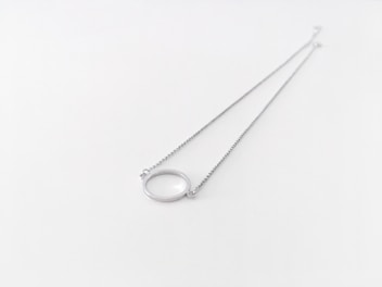 A delicate silver necklace with a sparkling pendant displayed on a rustic wooden surface.