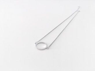 A silver pendant necklace resting on a marble surface.