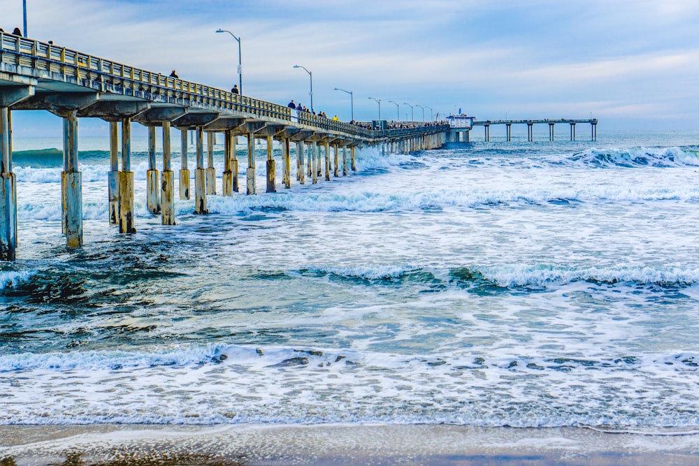 frothing waves beneath dock at beach