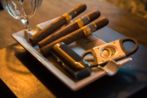 three cigar beside cutter on ashtray