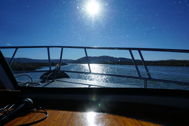 A happy boater adjusting a marine radio on a sunny day with the ocean in the background.