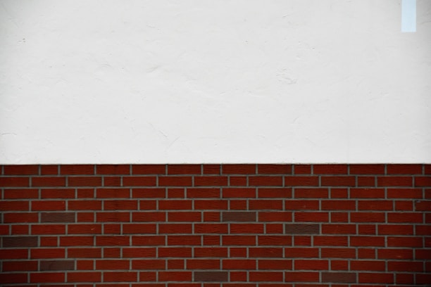 A simple composition featuring a horizontal division between a brick wall and a white plastered surface above.