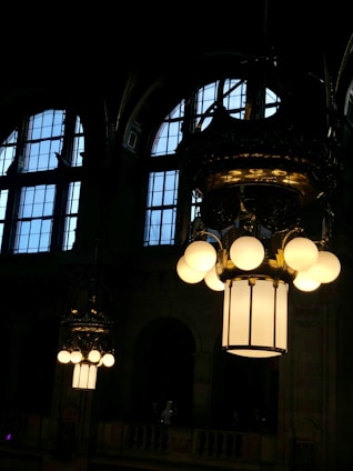 A skilled technician carefully installing a grand chandelier in a spacious room with vaulted ceilings bathed in soft natural light.