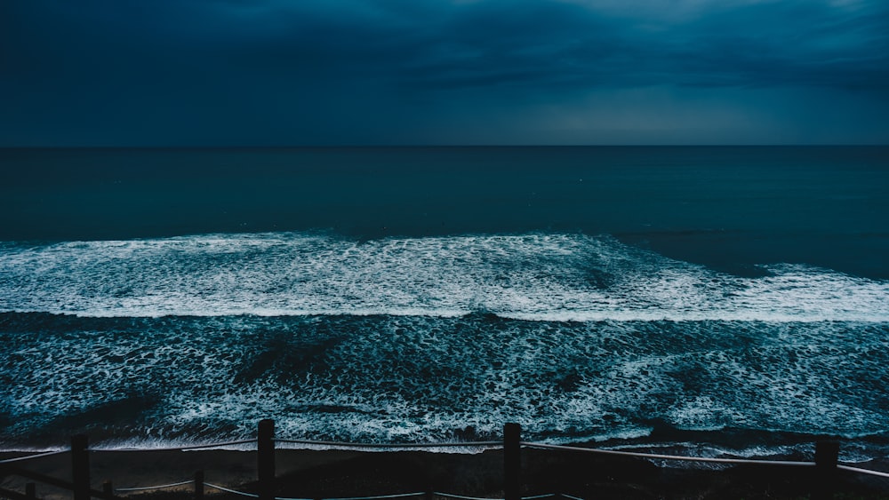 big waves overflowing the at barrier under dark sky