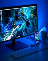 flat screen computer monitor turned on beside black keyboard