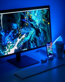 flat screen computer monitor turned on beside black keyboard