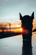 A close-up of a camera lens reflecting a vibrant sunset over a mountain range.
