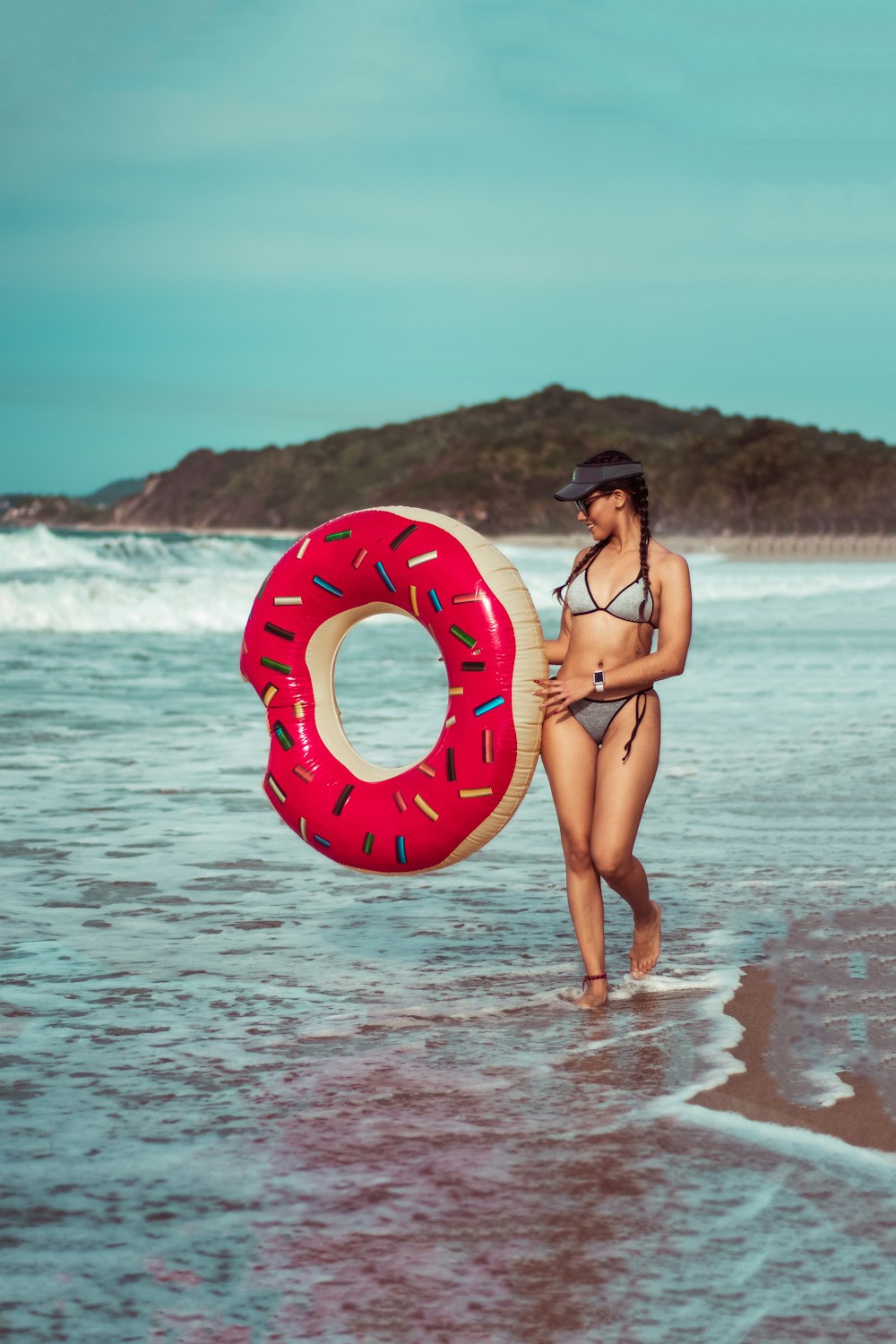 woman in gray bikini holding red and brown inflatable tube