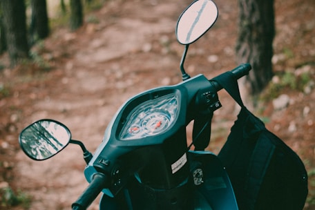 Close-up of a scooter's handlebars with a scenic backdrop.