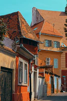 Historic village street with colorful houses and cobblestones, bathed in warm afternoon light.