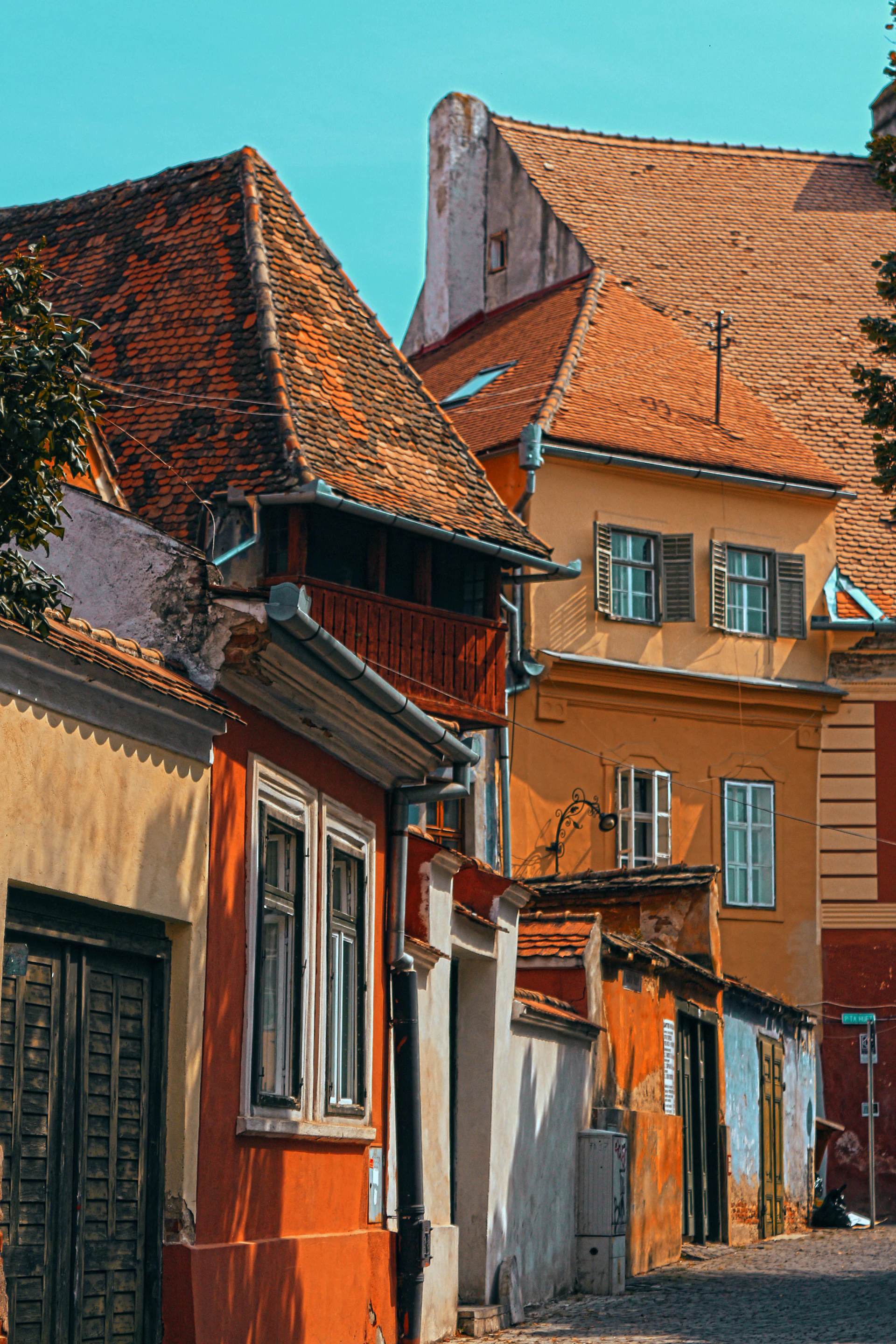 A charming medieval street in Sibiu, with colorful houses and cobblestone paths bathed in warm afternoon light.