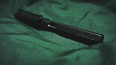 Close-up of a sleek emerald green promotional pen with golden accents on a clean white background.