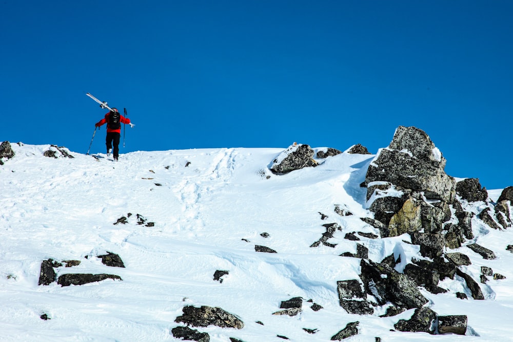 man carrying ski blades at top of mountain
