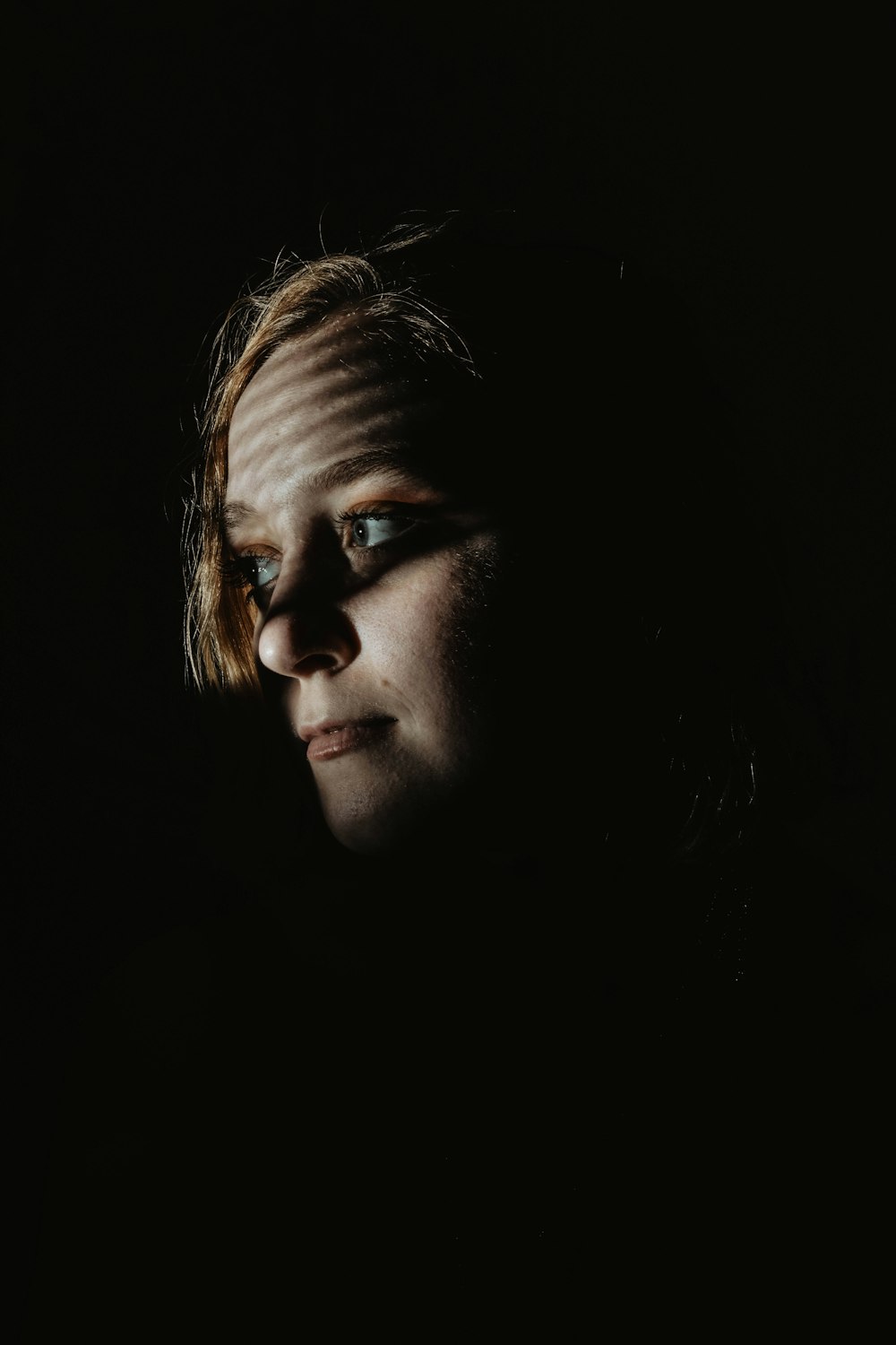 a woman's face is shown in the dark