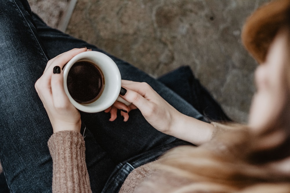 high angle photography of woman holding mug filled with brown substance