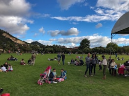 Families enjoying a sunny afternoon in a spacious outdoor park within the club.