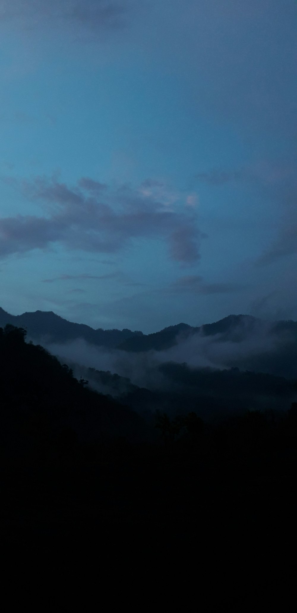 mountain covered with fogs under blue skies