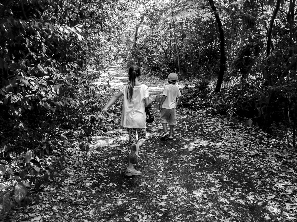 Photo en niveaux de gris d’un garçon et d’une fille marchant