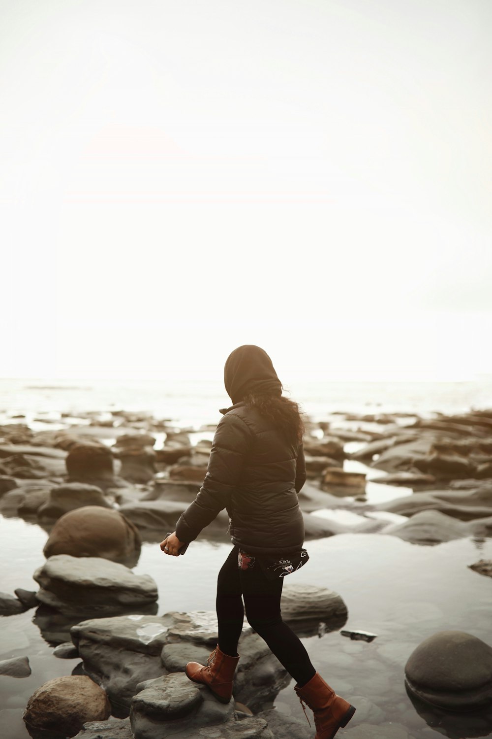 woman walking on black and brown rocks
