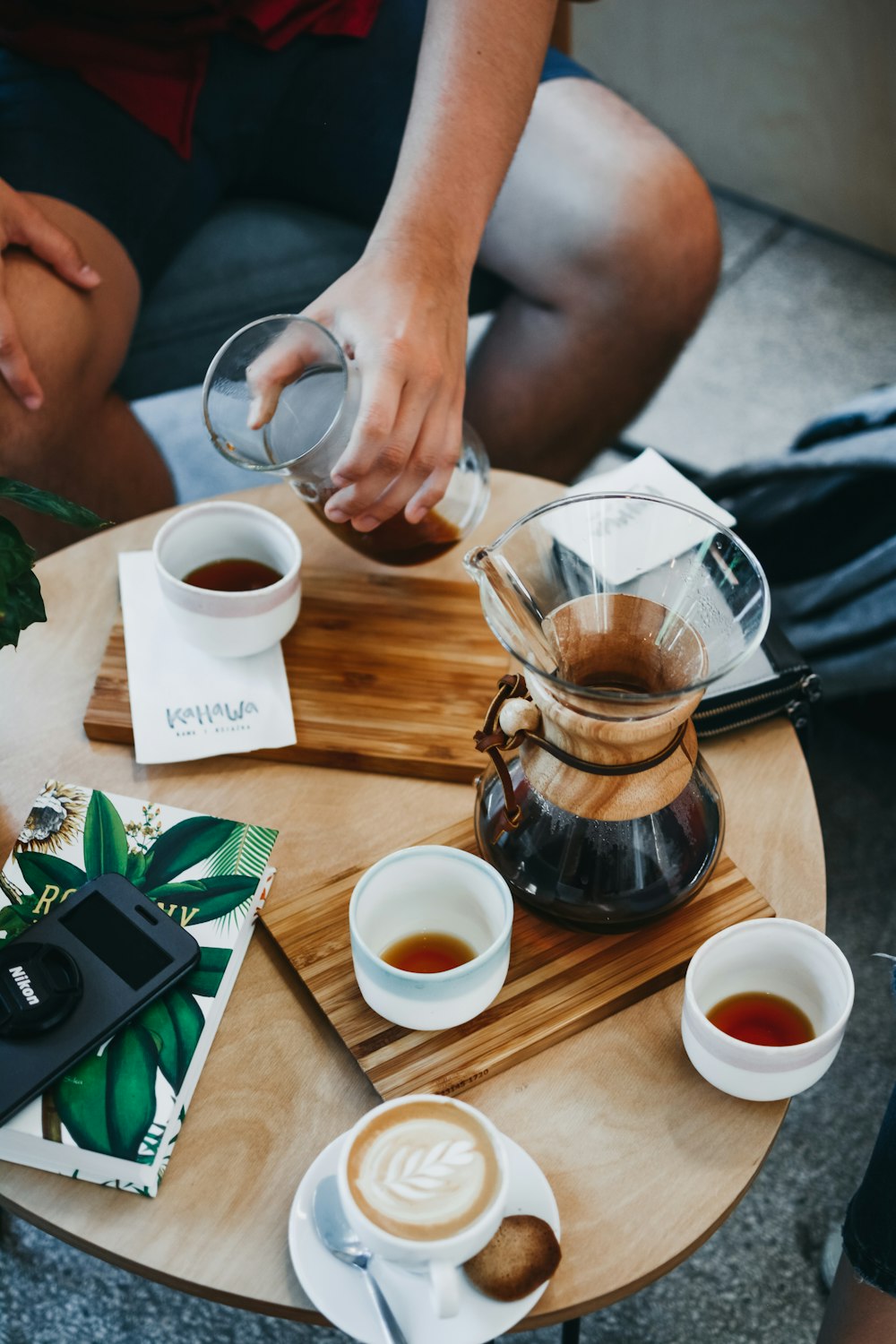 person about to pour tea on teaup while on coffee table