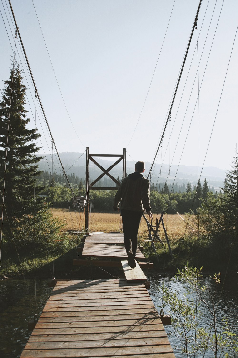 man walking on plank to cross bridge during daytime